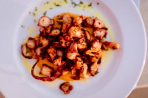 une assiette blanche de nourriture avec crevettes et sauce dans l'établissement Resort Faro di Punta Fenaio, à Campese