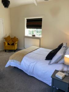 a bedroom with a white bed and a yellow chair at STABLE COTTAGE in Cheswardine