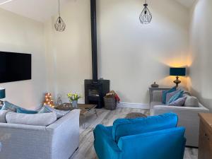 a living room with two blue chairs and a fireplace at STABLE COTTAGE in Cheswardine