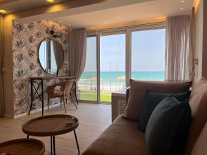 בית חוף מושלם עם גקוזי ומרפסת - Beachside Bliss W jacuzzi في حيفا: غرفة معيشة مع أريكة وإطلالة على المحيط