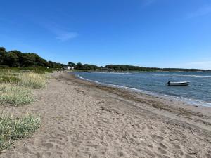 una playa de arena con un barco en el agua en Ny gårdsleilighet i Nevlunghavn, en Larvik