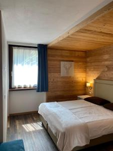 ein Schlafzimmer mit einem großen Bett und einem Fenster in der Unterkunft Chalet La Pineta in Santa Caterina Valfurva
