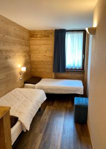 Duas camas num pequeno quarto com uma janela em Chalet La Pineta em Santa Caterina di Valfurva