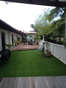 patio trasero con terraza de madera y patio con césped verde en Le Meilleur, en George Town