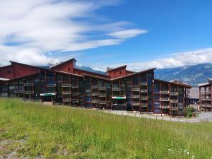 un grand bâtiment avec une bibliothèque avec des montagnes en arrière-plan dans l'établissement Appartement Les Arcs 1800, 2 pièces, 5 personnes - FR-1-411-694, à Bourg-Saint-Maurice