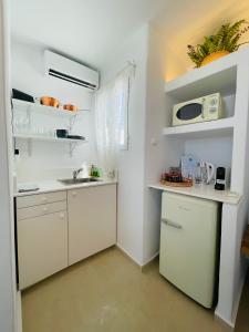 a kitchen with white cabinets and a sink and a microwave at Mykonian Starling - Town n' Sunset View Apartment in Mýkonos City