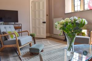 Poxwell Manor West Wing - Exclusive Dorset Retreat : غرفة معيشة مع إناء من الزهور على طاولة زجاجية