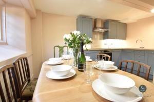 Poxwell Manor West Wing - Exclusive Dorset Retreat : طاولة طعام مع أطباق بيضاء وورود عليها