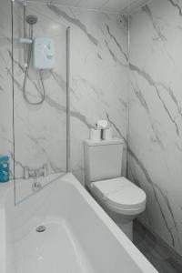 a white bathroom with a toilet and a shower at Riverview Cottage in Lanark