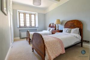 a bedroom with two beds and a window at Poxwell Manor West Wing - Exclusive Dorset Retreat 