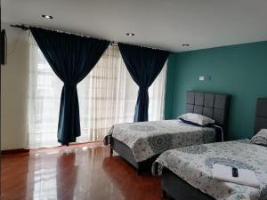 a bedroom with two beds and blue walls at Cornelio's House in Bogotá