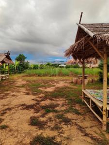ein Feld mit einer Hütte und einer Schotterstraße in der Unterkunft บ้านสวนกางโต้ง Ban Suan Kang Tong in Chom Thong