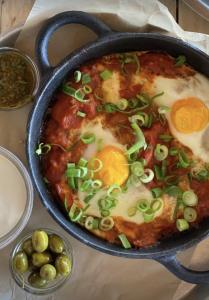 a pan of food with eggs and olives on a table at Dawar Sinai Bliss - Luxury Haven in Ma'ale Adumim