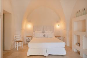 a white bedroom with a large bed with white pillows at Masseria Le Carrube in Ostuni +48 photos