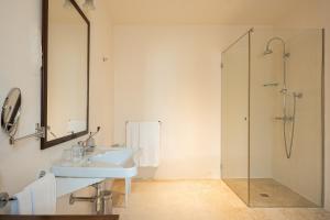 a white bathroom with a sink and a shower at Masseria Le Carrube in Ostuni