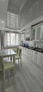 uma cozinha com armários brancos e uma mesa e cadeiras em Отличные апартаменты самом центре Алматы. Жилой комплекс Арбат em Almaty