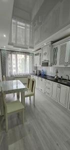 a kitchen with white cabinets and a table and chairs at ЖК Арбат в самом центре города in Almaty