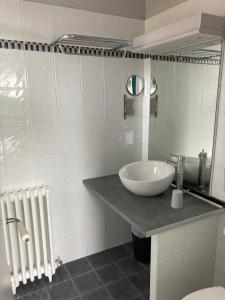 a white bathroom with a sink and a mirror at Hôtel Le Boïate in Arès