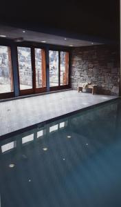 a large swimming pool in a house with windows at T2 Les Chardons avec Piscine Sauna et Hammam in Valloire