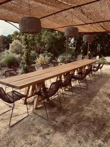 une grande table et des chaises en bois sous un parasol dans l'établissement Maison Drôles d'Oiseaux, à Plieux