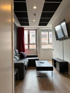 uma sala de estar com um sofá e uma televisão de ecrã plano em Aparthotel Montcada em Montcada i Reixac