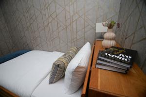 ein Bett mit einem Tisch mit einem Buch und einer Vase in der Unterkunft Apartmani Čarolija in Lučani