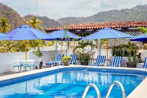 巴亞爾塔港的住宿－Hotel Pueblito Vallarta，一个带蓝色椅子和遮阳伞的游泳池
