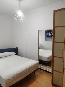 een slaapkamer met een spiegel, een bed en een lamp bij Bajo al lado del Ayuntamiento in Santander