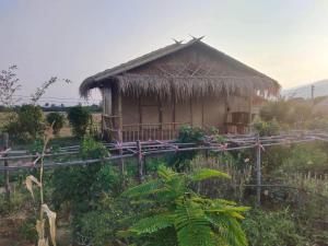 eine kleine Hütte mit Strohdach auf einem Feld in der Unterkunft บ้านสวนกางโต้ง Ban Suan Kang Tong in Chom Thong
