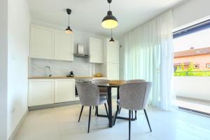 a kitchen with white cabinets and a table and chairs at Apartments La Scogliera Rovinj in Rovinj