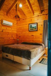 1 dormitorio con 1 cama en una habitación de madera en Irová Apart Hotel en Posadas