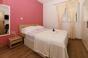 1 dormitorio con cama blanca y pared rosa en Blue home en Makarska