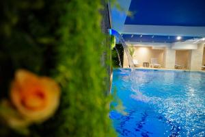 a swimming pool with a water fountain in the foreground at Doanesia Premium Hotel & Spa in Tirana