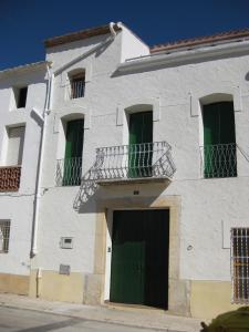 ein weißes Gebäude mit grünen Türen und einem Balkon in der Unterkunft Ca La Partida in San Rafael del Río