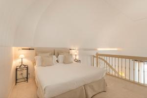 een slaapkamer met een groot bed met witte lakens en kussens bij Masseria Le Carrube in Ostuni