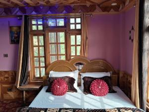 1 dormitorio con cama de madera y almohadas rojas en Cozee Mozee Family Homestay en Kūfrī