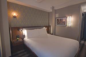 a bedroom with a white bed and a green wall at Hotel Edison Times Square in New York