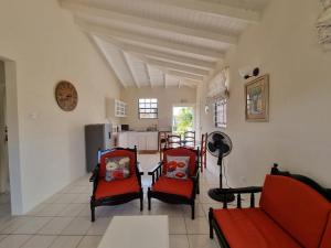 ein Wohnzimmer mit 2 roten Stühlen und eine Küche in der Unterkunft Coastal View 7 Apartments in Christchurch