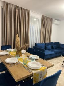 un soggiorno con tavolo e divano blu di Pine Apartments at San Pietro Resort a Durrës