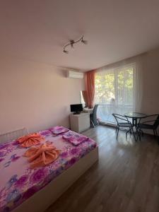 a bedroom with a bed and a table and a window at Bogdanovi Guest House in Chernomorets