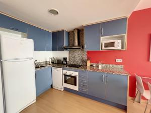 uma cozinha com armários azuis e uma parede vermelha em Royal Marine II 136 - Piso con piscina comunitaria em Empuriabrava