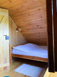 een klein houten bed in een houten kamer bij Domek z prywatną plażą i sauną in Mikołajki