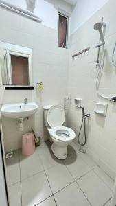 uma casa de banho branca com um WC e um lavatório em Spice Arena Guesthouse em Bayan Lepas