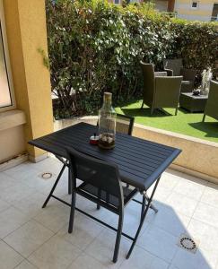 uma mesa preta e uma cadeira com uma garrafa em Joli T2 ,50 m des plages, 4 pers , en rez de jardin em Fréjus
