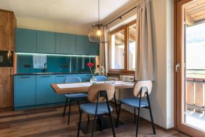 una cocina con armarios azules y una mesa y sillas de madera. en Apartments Karbon, en Castelrotto