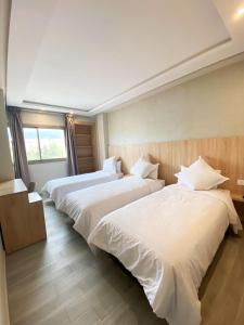 Cette chambre d'hôtel comprend 3 lits avec des draps blancs. dans l'établissement HOTEL PALACE AL SALAM , Beni Mellal, à Béni Mellal