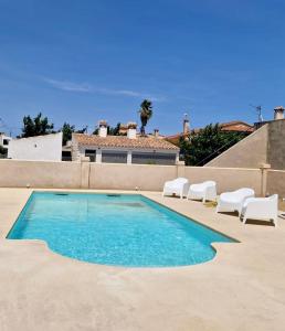 a swimming pool with two white chairs and a house at Villa Barracot in Deltebre