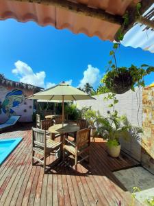 eine Holzterrasse mit einem Tisch, Stühlen und einem Sonnenschirm in der Unterkunft chale aparecida dos milagres in São Miguel dos Milagres