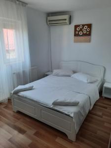 a white bed in a room with a window at Casa Loro in Eforie Sud