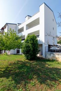 a white building with trees in front of it at Apartments La Scogliera Rovinj in Rovinj